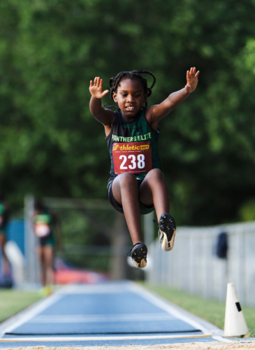 Young Panthers Elite athlete jumping during track and field event.